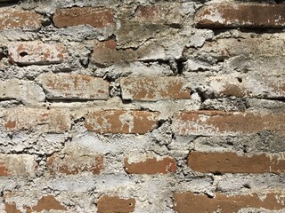An old wall that looks like an arrangement of bricks that have not been coated with cement, and there are some cracks.