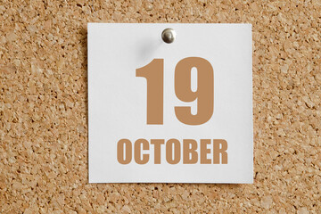 october 19. 19th day of the month, calendar date.White calendar sheet attached to brown cork board.Autumn month, day of the year concept
