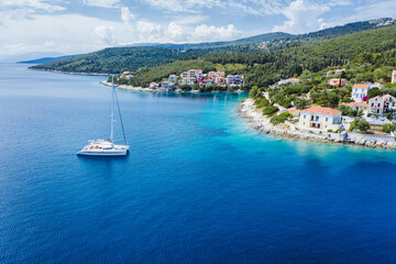 Fototapeta na wymiar Sailing yacht boat in blue sea arrive Fiscardo village in Kefalonia island, Greece