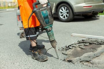 He removes the asphalt with a jackhammer. Removing the asphalt layer from the road.
