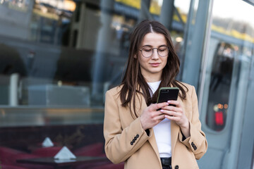 An attractive young woman walking in the city center, texting and laughing. Woman entrepreneur taking a break from work checking her cell phone.