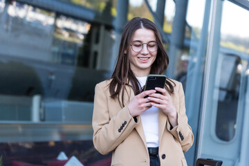 An attractive young woman walking in the city center, texting and laughing. Woman entrepreneur taking a break from work checking her cell phone.