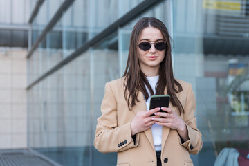 An attractive young woman walking in the city center, texting and laughing. Woman entrepreneur taking a break from work checking her cell phone.