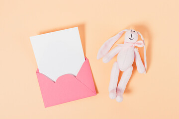Toy bunny and pink envelope with white blank card