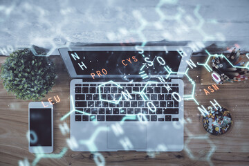 Physics and math theme hologram with formula drawings over computer on the desktop background. Top...