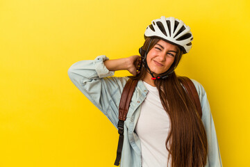 Young student caucasian woman wearing a bike helmet isolated on yellow background touching back of head, thinking and making a choice.