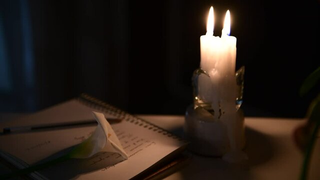 4k The candle is burning, on the table lies a notebook with verses, a pen and a white calla lilly flower. Write at night, inspiration, creativity, poetry
