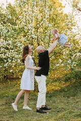 A happy young family with one small child walking having fun laughing spending time together in the park in nature on vacation in the summer outdoors, family day