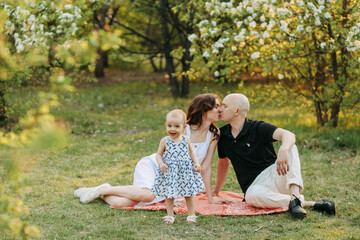 A happy young family with one small child walking having fun laughing spending time together in the park in nature on vacation in the summer outdoors, family day