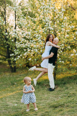 A happy young family with one small child walking having fun laughing spending time together in the park in nature on vacation in the summer outdoors, family day