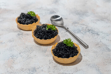 Black caviar in tartlets on a light background. Healthy food concept.