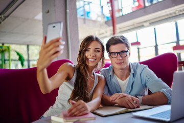 Cheerful hipster guys smiling at camera while shooting together influence vlog connecting to 4g wireless indoors, portrait of happy Caucasian best friends posing while clicking selfie images