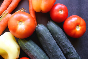 Zucchini, tomatoes, peppers, carrots and cucumbers on dark background. Flat lay.