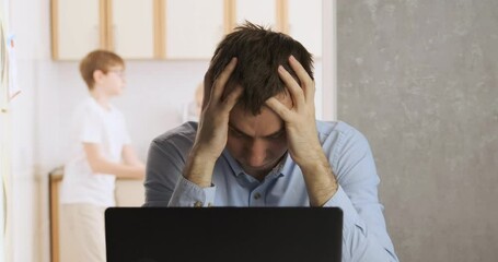 Man works at home and tries to concentrate while the children are making noise. Sons interferes with fathers work.