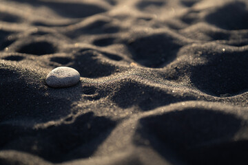A stone on the black sand of a volcanic beach at sunset. concept of peace, tranquility, relaxation.