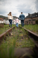 Fototapeta na wymiar Family with child walking along the railroad, view from behind.