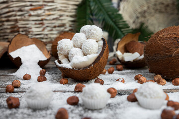 Coconut candy, balls, coconuts and hazelnuts on a rustic wooden surface