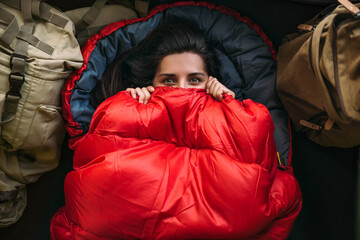 A young woman in a comfortable sleeping bag in a tent, top view. A tourist in a sleeping bag. A...