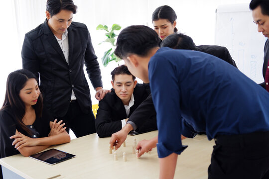 Asian Senior manager is meeting and brainstorming with staff and teamwork about project with chesses in plan. Businesspeople are planning marketing to reach the goal. Business and economics concept.
