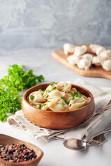 Homemade meat dumplings with onions and parsley- russian pelmeni in wooden bowl.