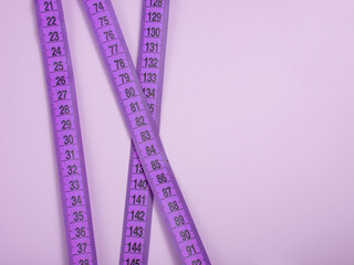 Bright purple tape measure on violet background with copyspace