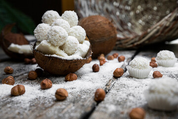 Obraz na płótnie Canvas Coconut candy, balls, coconuts and hazelnuts on a rustic wooden surface