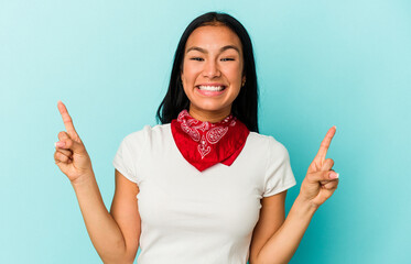 Young Venezuelan woman isolated on blue background indicates with both fore fingers up showing a...