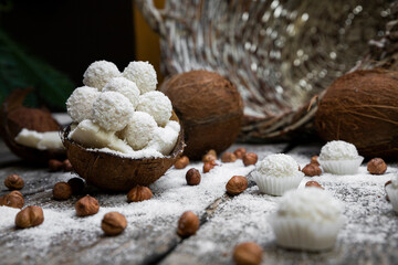 Coconut candy, balls, coconuts and hazelnuts on a rustic wooden surface