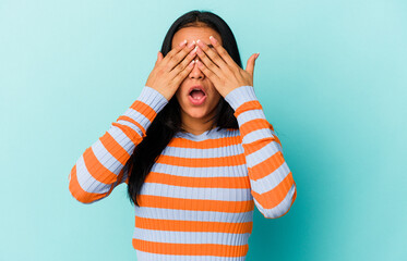 Young Venezuelan woman isolated on blue background covers eyes with hands, smiles broadly waiting for a surprise.