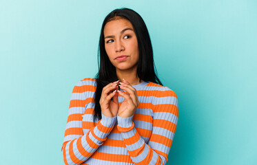 Young Venezuelan woman isolated on blue background making up plan in mind, setting up an idea.