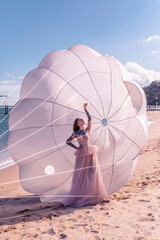 Beautiful woman with white parachute at the beach
