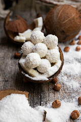 Coconut candy, balls, coconuts and hazelnuts on a rustic wooden surface