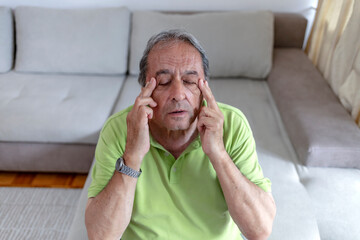 Close up face of elderly 70s man massaging temples closed eyes reduces intense intermittent...