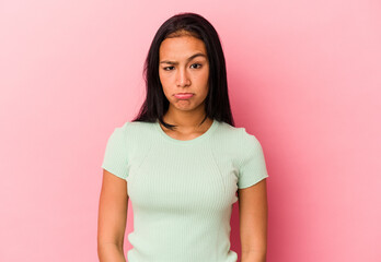 Young Venezuelan woman isolated on pink background sad, serious face, feeling miserable and...