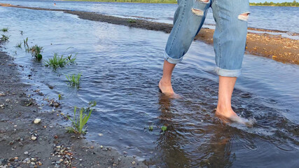 Female legs walking barefoot in river and connecting with nature