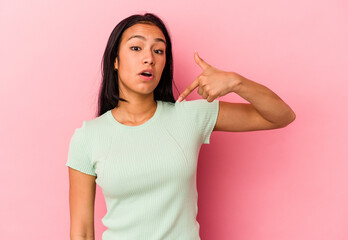 Young Venezuelan woman isolated on pink background person pointing by hand to a shirt copy space, proud and confident