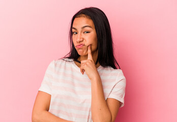 Young Venezuelan woman isolated on pink background unhappy looking in camera with sarcastic expression.