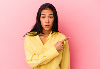 Young Venezuelan woman isolated on pink background pointing to the side