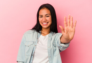Young Venezuelan woman isolated on pink background smiling cheerful showing number five with fingers.