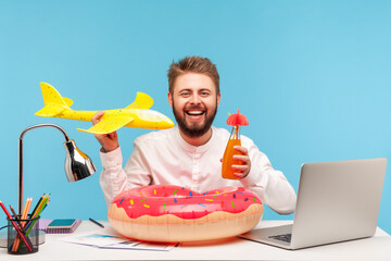 Positive smiling bearded man sitting at workplace with lifebuoy holding bottle with lemonade and...