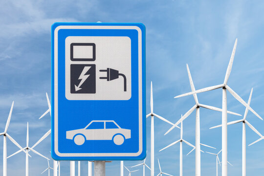 Dutch sign for charging an electric car in front of a large wind turbine farm