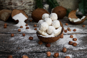 Coconut candy, balls, coconuts and hazelnuts on a rustic wooden surface
