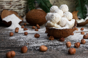 Coconut candy, balls, coconuts and hazelnuts on a rustic wooden surface