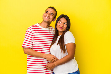 Naklejka premium Young latin couple isolated on yellow background dreaming of achieving goals and purposes