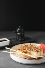 Tuna sushi in white dish served with soy and wasabi sauce, pickled ginger. Sushi set with tuna shavings on top.