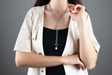 Decoration on a woman's neck. The girl touches the chain around her neck with her hand. Close-up.
