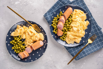 Breakfast with scrambled egg, sausages and green peas on white plate