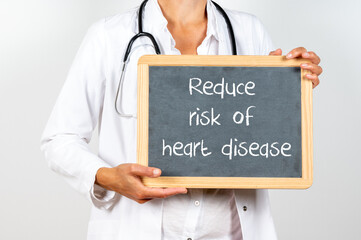 Doctor holding a blackboard with Reduce risk of heart disease text