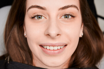 Close-up, cropped snapshot of beautiful woman's face with perfect smile. At dentist appointment. Teeth whitening. Top view. Healthy teeth concept