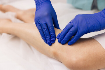 Fototapeta premium Healthcare medical insurance concept. Physiotherapist worker woman assisting physical medical exercise recovery after injuries. Doctor in gloves examining painful knee of female patient leg trauma